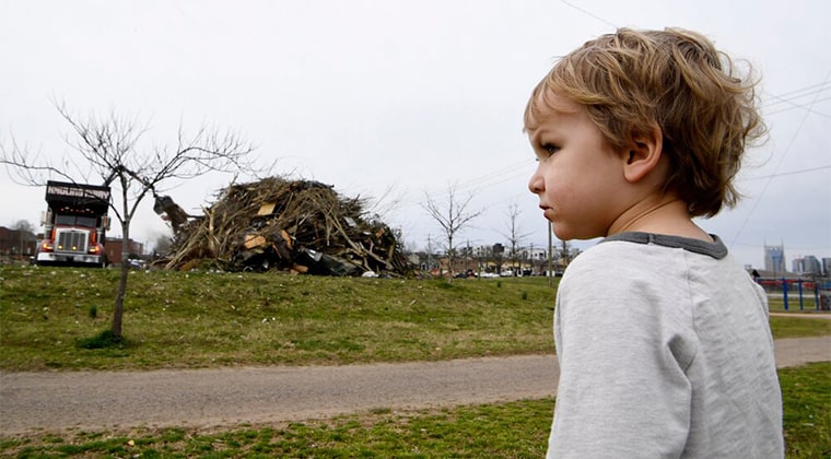 A worried child looks at collapse debris in the aftermath of a natural disaster